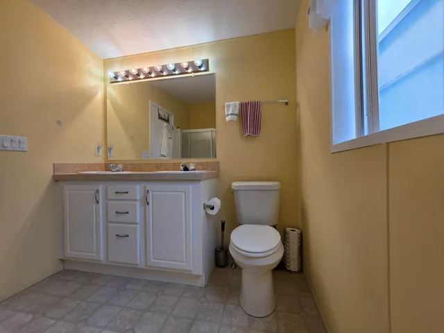 a bathroom with a granite countertop sink mirror vanity and toilet
