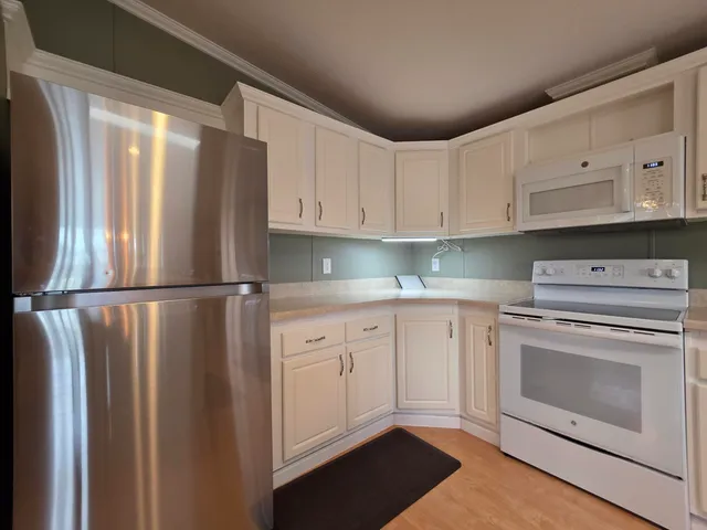 a kitchen with cabinets stainless steel appliances and a refrigerator