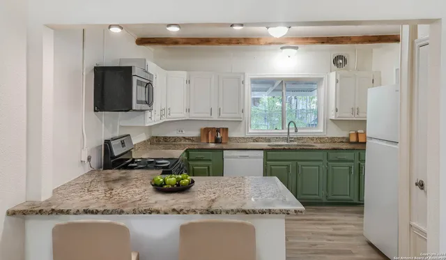 a kitchen with kitchen island granite countertop a sink a counter top space and cabinets