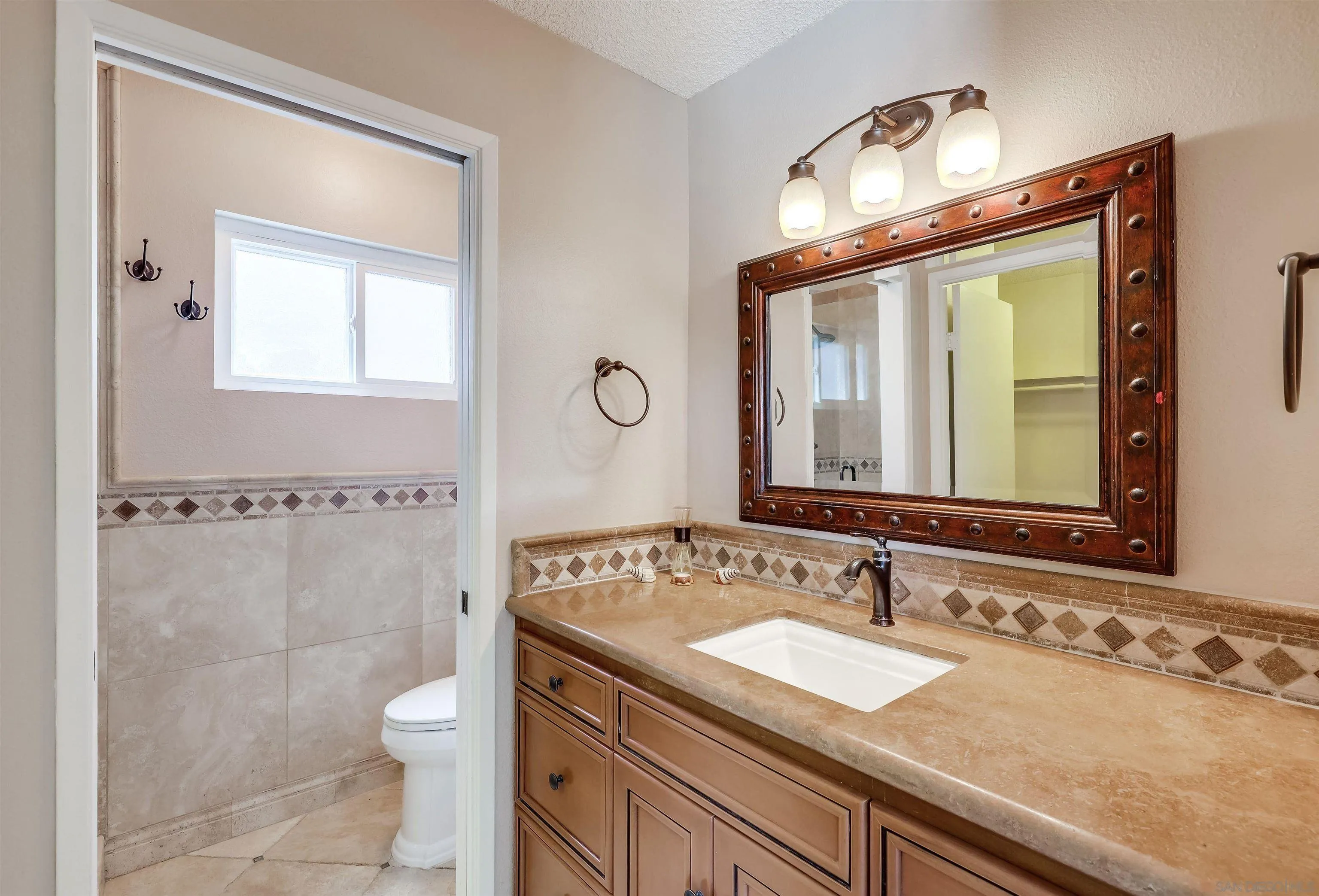 14039 Hermosillo Way Poway, CA 92064 - Photo 15 of 31 a bathroom with a granite countertop sink a toilet and a mirror