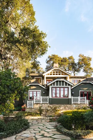 a front view of a house with a garden and trees