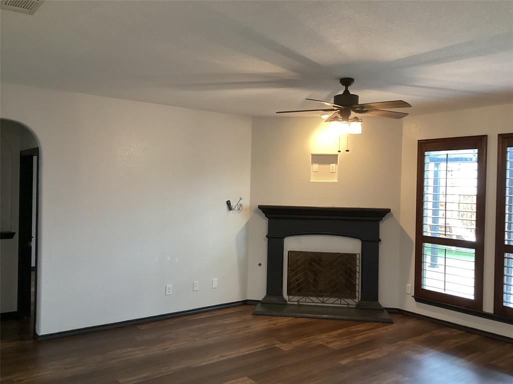 10320 Point Lobos Trail Fort Worth, TX 76177 - Photo 11 of 33 Living space featuring wood-finish flooring, a fireplace with a dark mantel, and plantation shutters on multiple windows