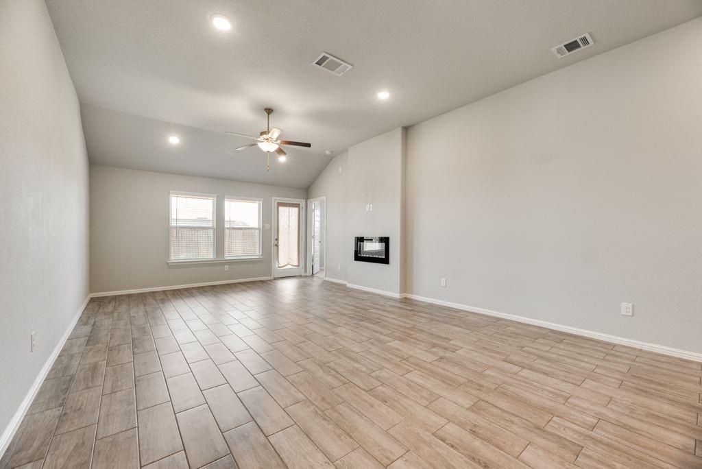 14216 Aberavon Drive Pilot Point, TX 76258 - Photo 9 of 19 Spacious room featuring wood-finish tile flooring, vaulted ceiling, recessed lighting, and a built-in fireplace
