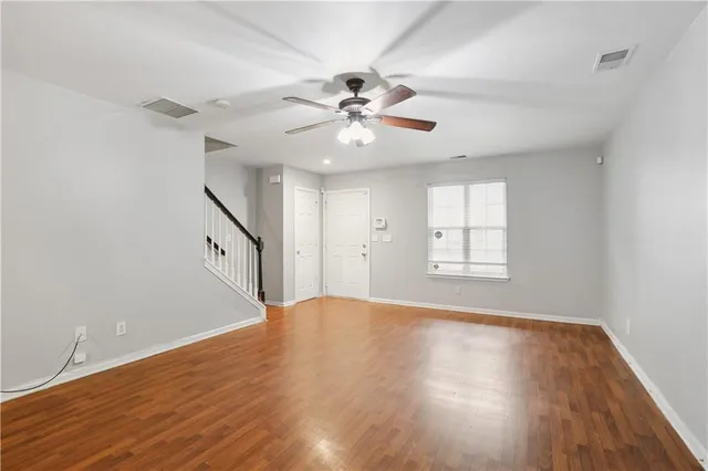 a view of an empty room with window and wooden floor