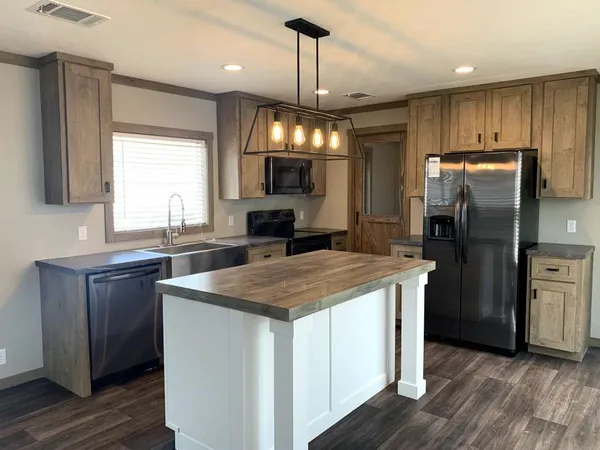 a kitchen with kitchen island a counter space a sink appliances and cabinets