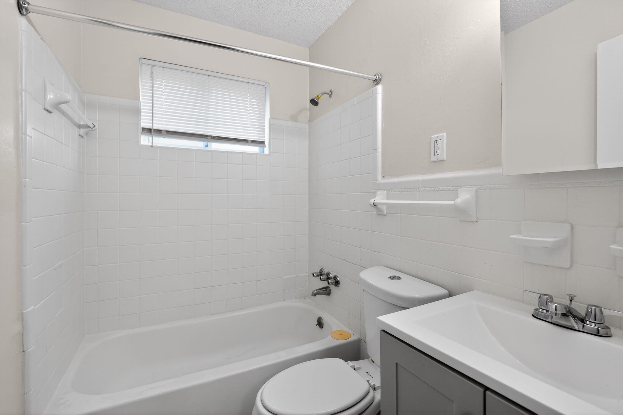 3603 England Street Memphis, TN 38127 - Photo 28 of 36 Full bath with vanity, a textured ceiling, washtub / shower combination, tile walls, and a wainscoted wall