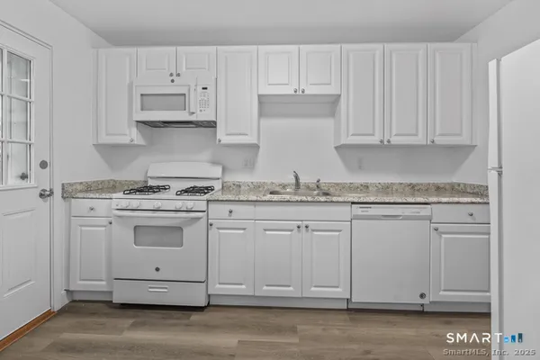 a kitchen with granite countertop white cabinets and white appliances