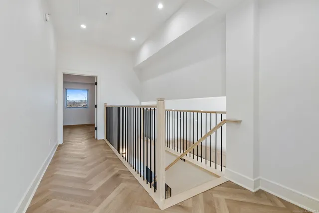 a view of a hallway with wooden floor and a bathroom