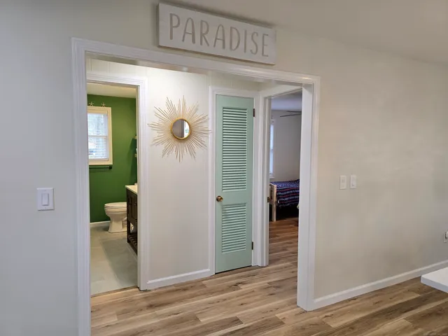 a view of a hallway with wooden floor and a bathroom