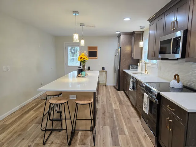 a kitchen with stainless steel appliances a dining table chairs sink and wooden floor