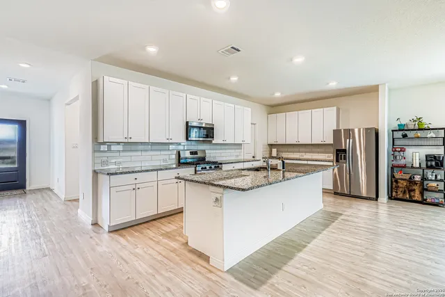 a kitchen with stainless steel appliances granite countertop a stove a sink and a refrigerator