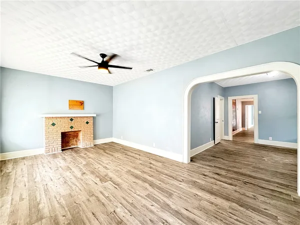 a view of a livingroom with a fireplace a ceiling fan and wooden floor