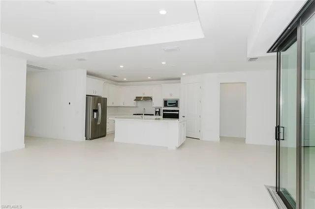 a view of kitchen with refrigerator and white cabinets