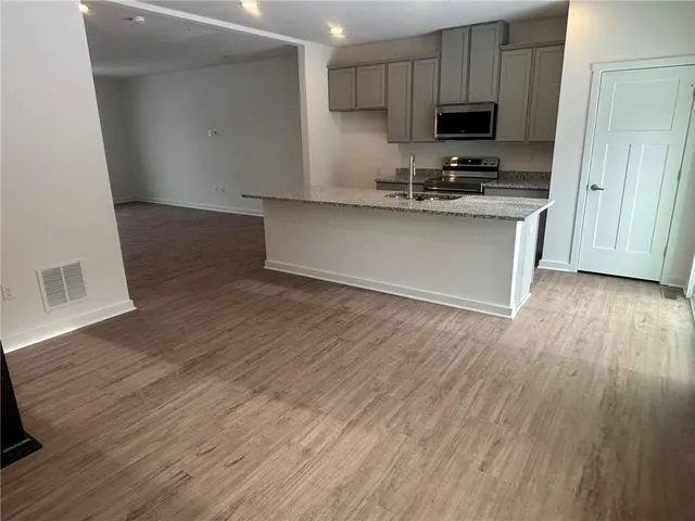 a kitchen with stainless steel appliances a stove top oven a sink and a hard wood floor