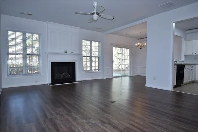 an empty room with wooden floor fireplace and windows