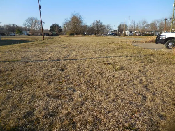 a view of dirt field with parked cars