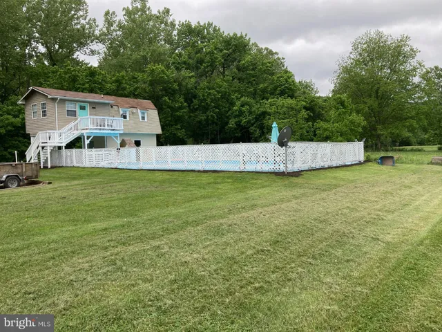 a view of a white house with a small yard and potted plants