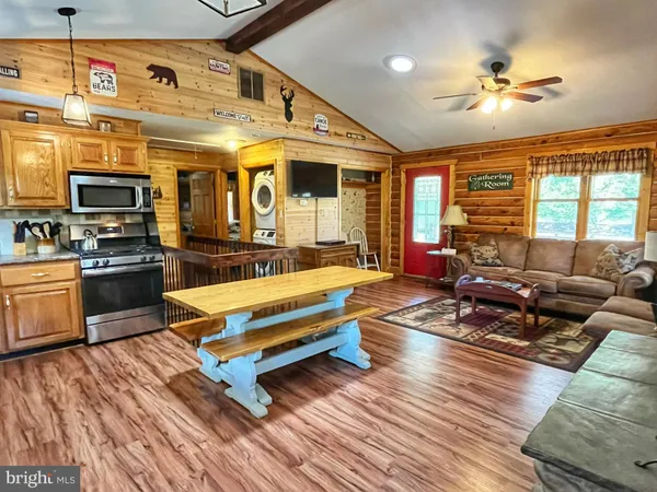 a living room with stainless steel appliances kitchen island granite countertop furniture and a wooden floor