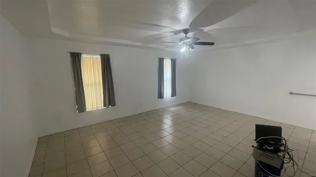 en empty room with windows and chandelier fan