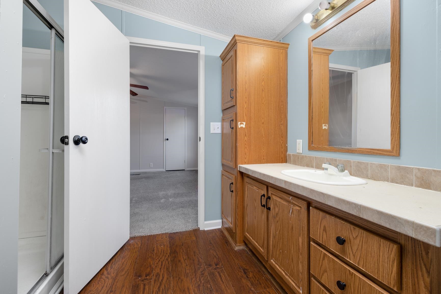 1029 Faulkner Road Atoka, TN 38004 - Photo 11 of 26 Bathroom with vanity, crown molding, ceiling fan, a textured ceiling, and wood-type flooring
