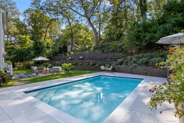 a view of a patio with couches table and chairs under an umbrella with a small yard