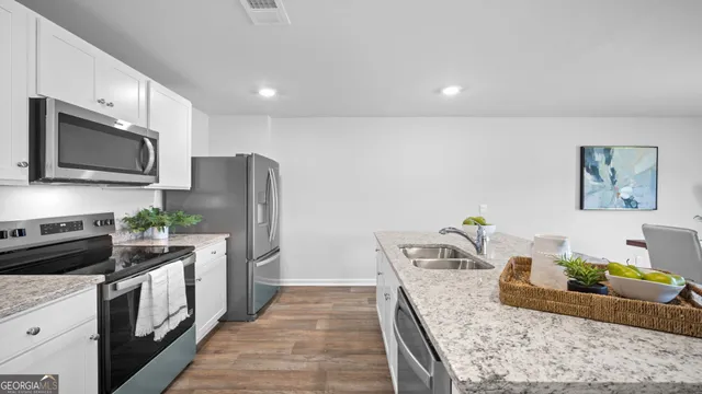 a kitchen with a refrigerator a stove a microwave and island with wooden floor