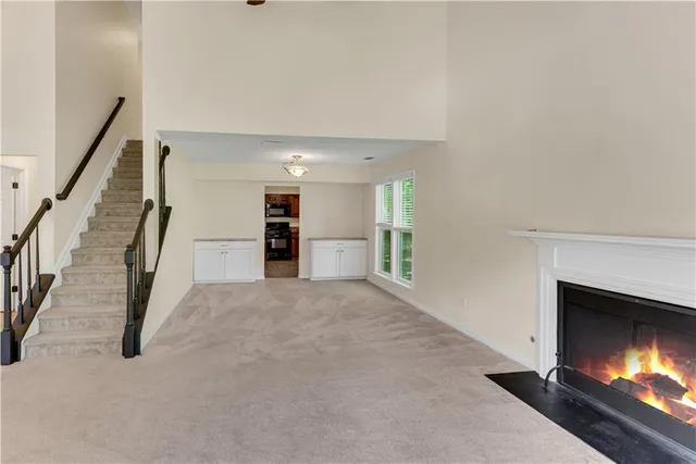 a view of an empty room with fireplace and stairs