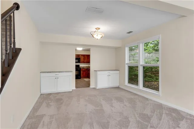 a view of an empty room with a window and cabinet