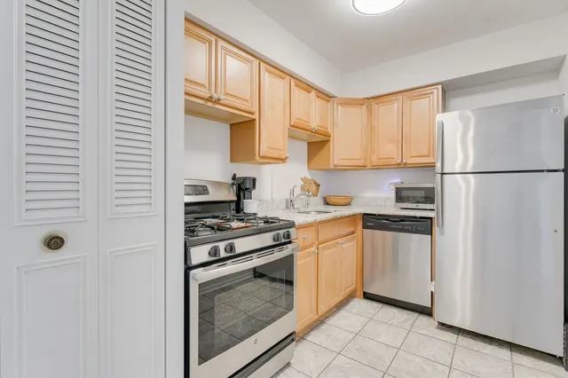 a kitchen with cabinets stainless steel appliances and a window