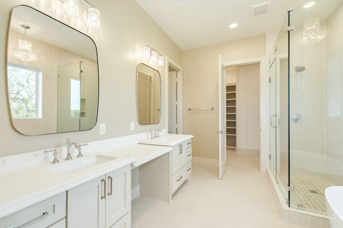 1737 Flintlock Court Angleton, TX 77515 - Photo 26 of 47 This spacious and elegant bathroom features dual sinks with modern fixtures, large mirrors, and chic pendant lighting. It includes a walk-in shower with glass doors and a neutral color palette for a serene atmosphere.