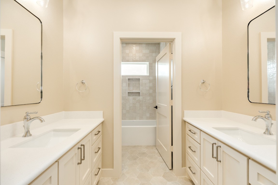 1737 Flintlock Court Angleton, TX 77515 - Photo 42 of 47 Bright bathroom with dual sinks and vanities, custom cabinetry, and a bathtub/shower combo. Neutral tones create a clean, inviting space. The tub is a deep tub perfect for soaking.