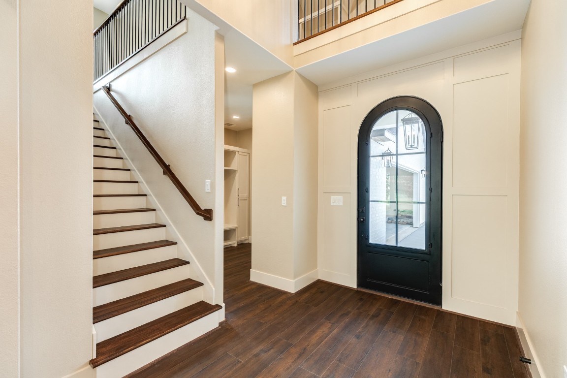 1737 Flintlock Court Angleton, TX 77515 - Photo 9 of 47 This elegant entryway features a dark wood floor and staircase, complemented by a striking black arched door with glass panes, creating a welcoming and stylish first impression.