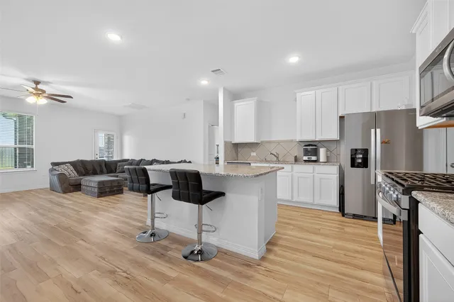 a kitchen with a refrigerator and white cabinets