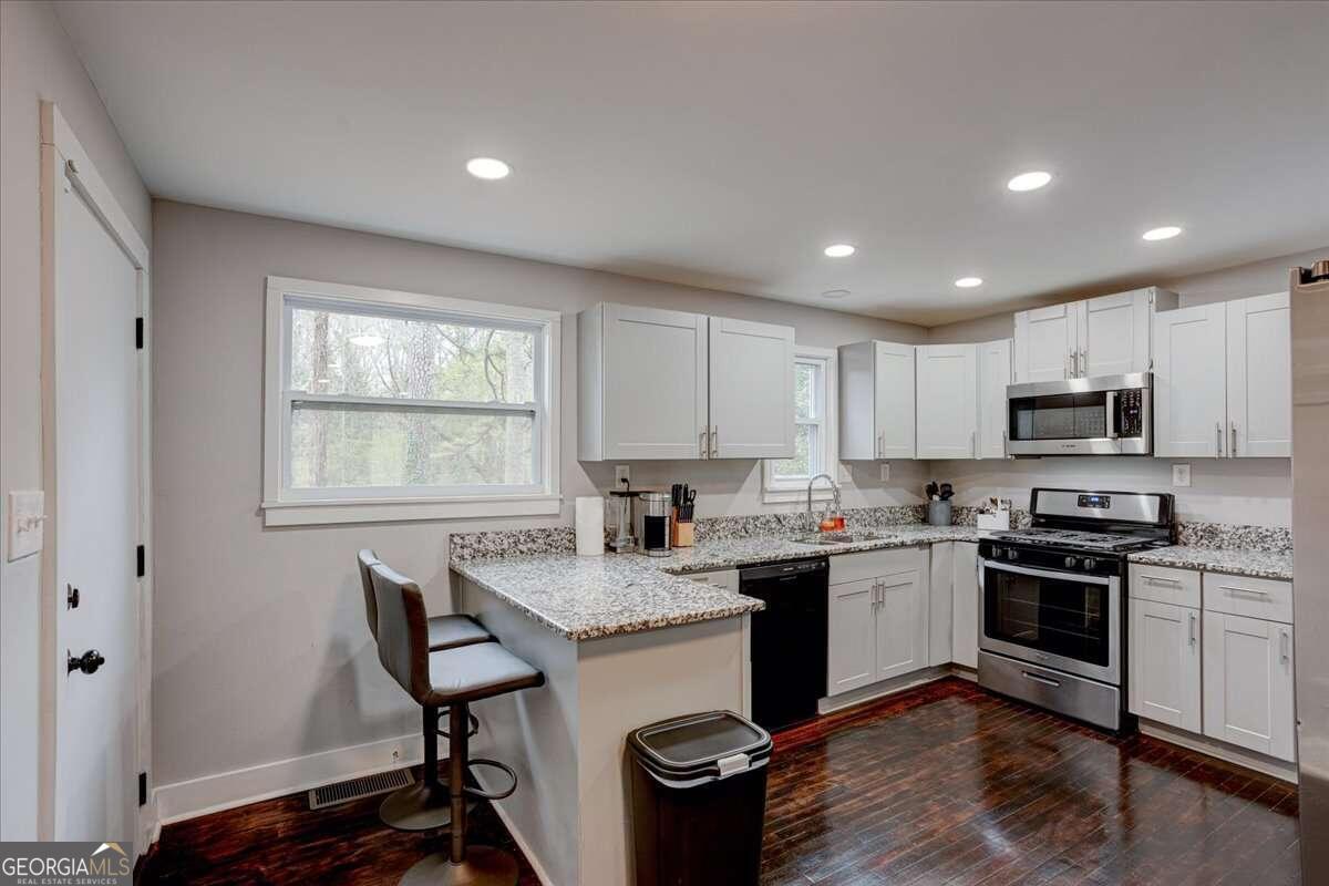 130 Mount Zion Road Southwest Atlanta, GA 30354 - Photo 7 of 22 a kitchen with stainless steel appliances granite countertop a stove a sink dishwasher a microwave oven and a refrigerator with wooden floor