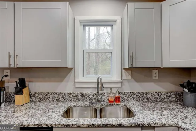 a kitchen with granite countertop a sink a window and cabinets