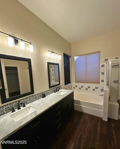 a bathroom with a tub a double vanity sink and mirror