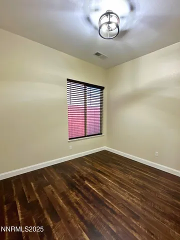 a view of an empty room with window and wooden floor
