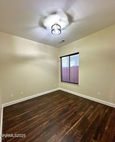 a view of an empty room with window and wooden floor