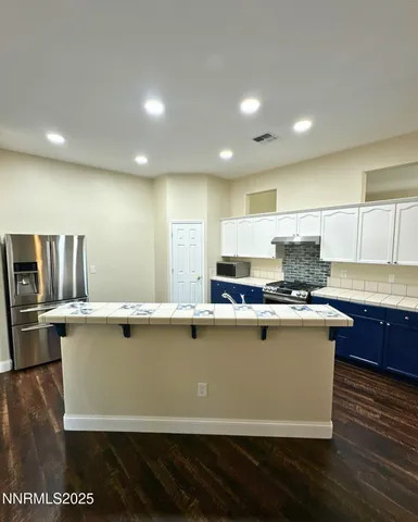 a kitchen with kitchen island stainless steel appliances a sink a stove a counter top space and cabinets