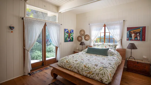 a bedroom with a bed wooden floor and a large window