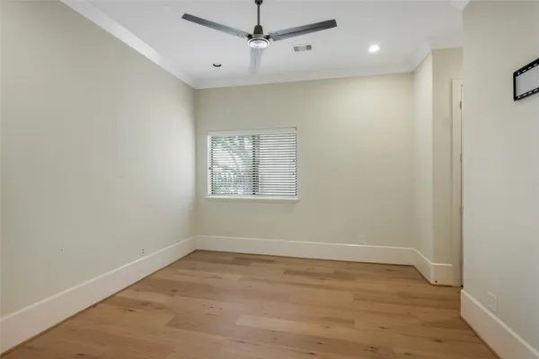 an empty room with wooden floor ceiling fan and windows
