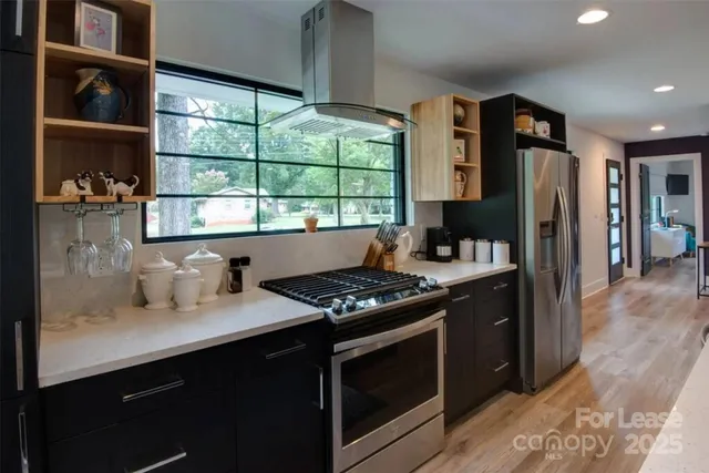 a kitchen with stainless steel appliances a stove sink and wooden floor