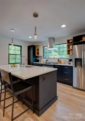 a kitchen with stainless steel appliances granite countertop wooden cabinets a sink a stove a refrigerator and island