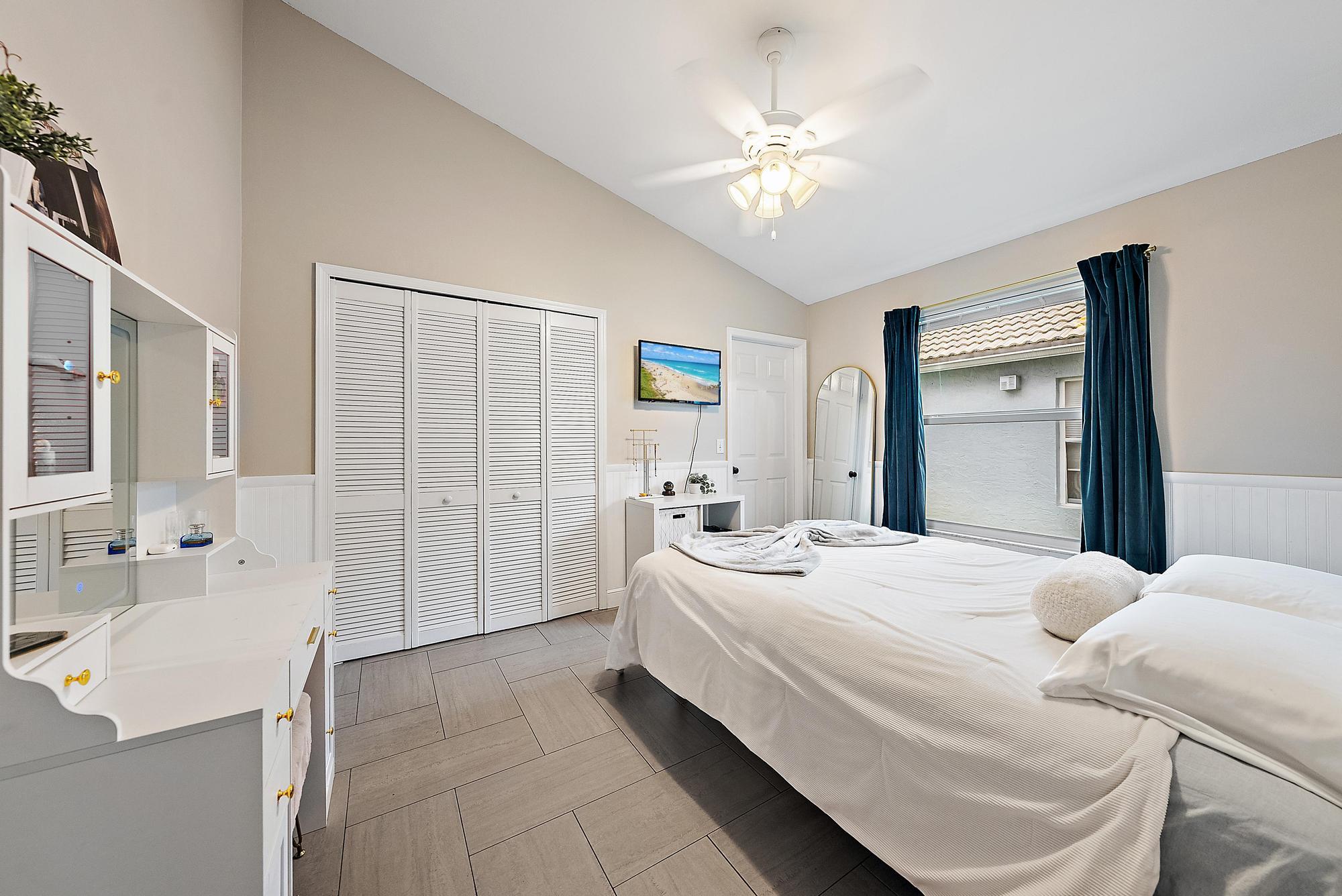 112 Spoonbill Court Jupiter, FL 33458 - Photo 15 of 28 a bedroom with a bed and a chandelier