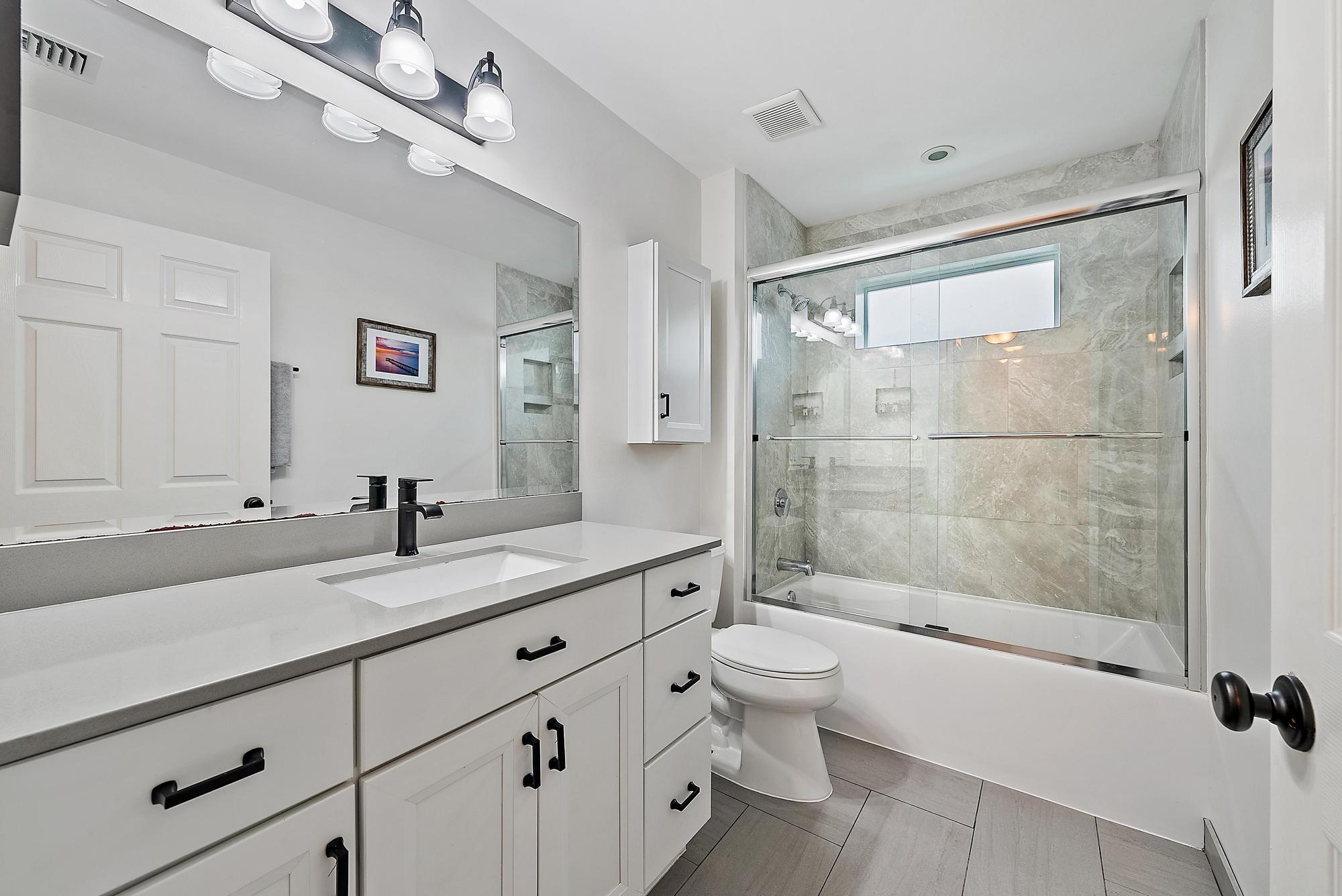 112 Spoonbill Court Jupiter, FL 33458 - Photo 17 of 28 a bathroom with a granite countertop sink a toilet a mirror and shower