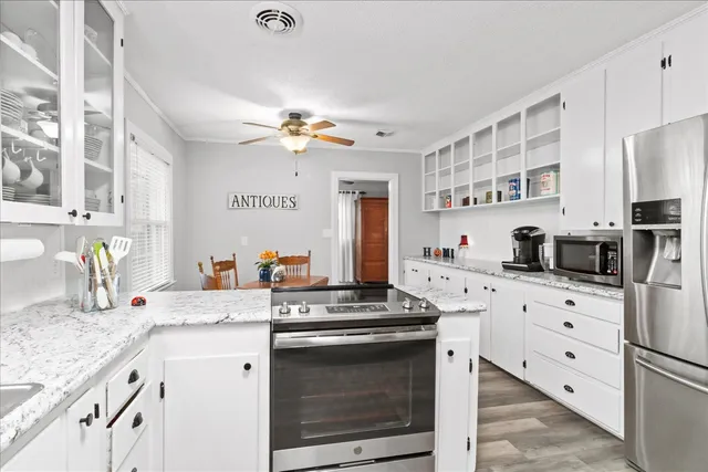 a kitchen with stainless steel appliances kitchen island granite countertop a sink dishwasher stove and refrigerator with wooden floor