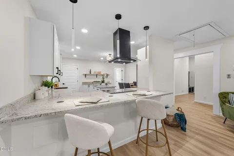 a kitchen with a dining table chairs and wooden floor