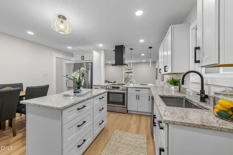 a kitchen with stainless steel appliances granite countertop a refrigerator a stove and a sink with wooden floor