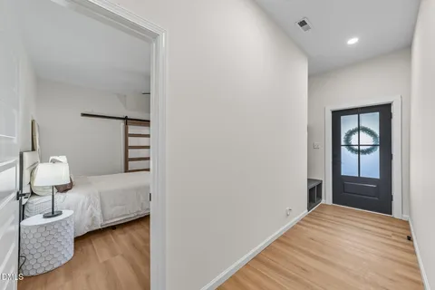 a bedroom with a bed and dresser with wooden floor