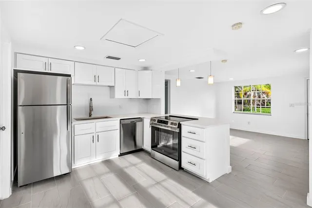 a kitchen with a refrigerator a stove top oven and white cabinets